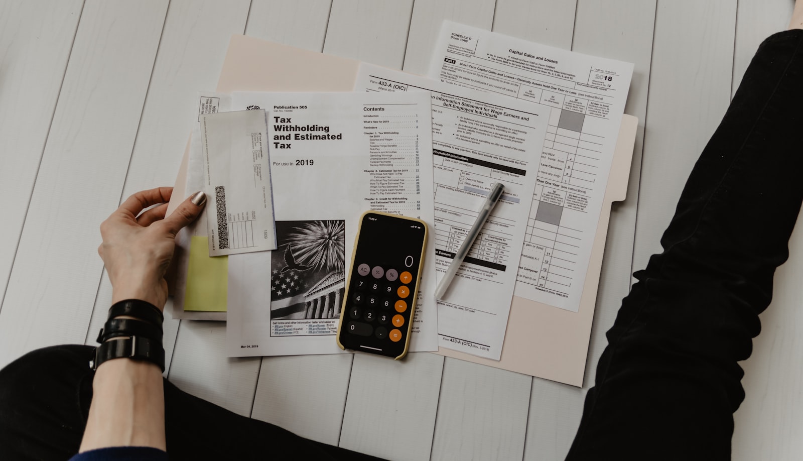 Person reviewing accounting documents and tax forms at a desk