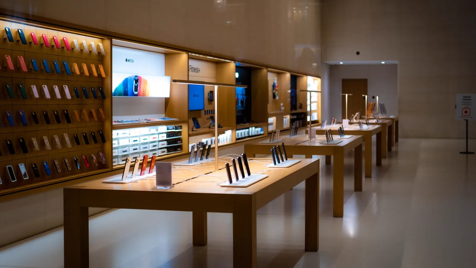Device store with smartphones on display tables and a wall of phone accessories